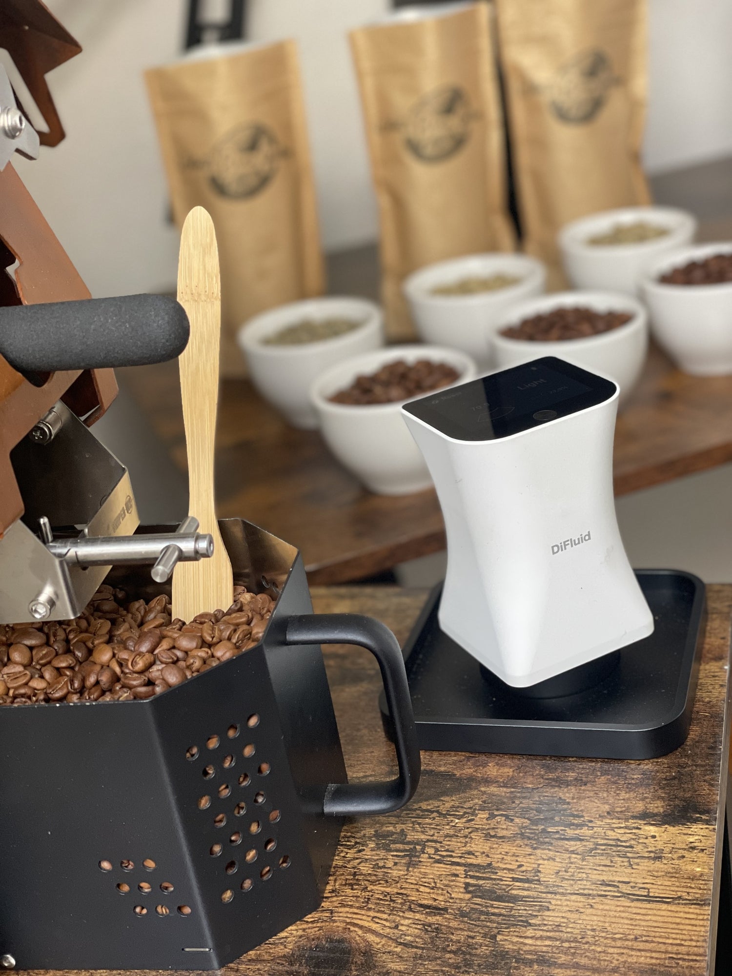 Coffee Roaster with coffee beans and a Colourimeter on a wooden surface used to analyse the colour of the coffee beans for consistency..
