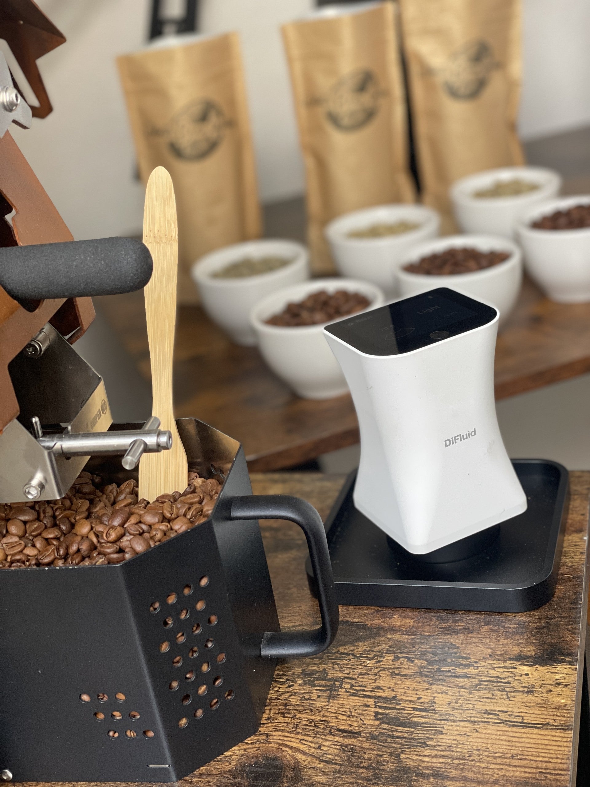 Coffee Roaster with coffee beans and a Colourimeter on a wooden surface used to analyse the colour of the coffee beans for consistency..
